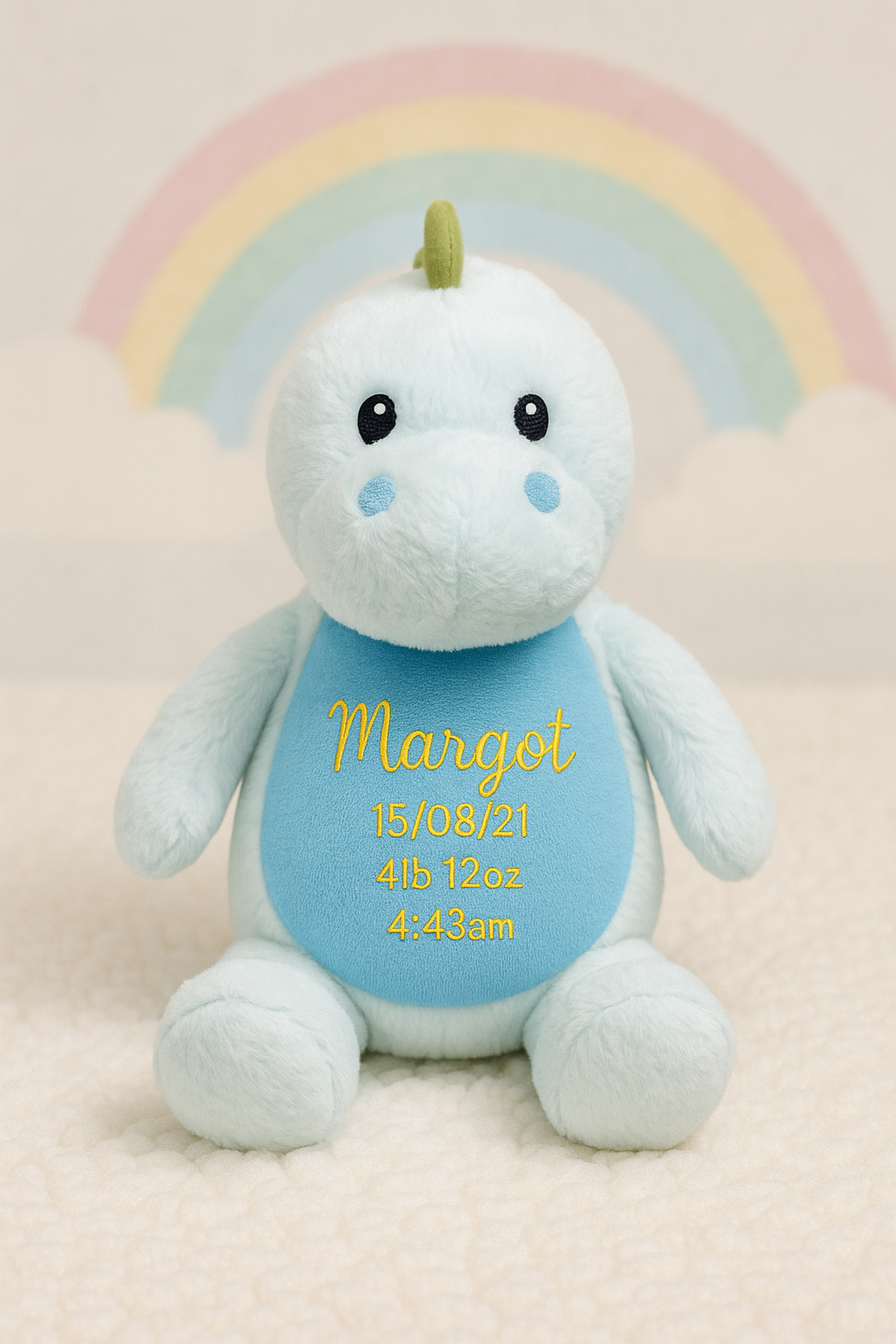 Soft white plush dinosaur with Margot bib and birth weight blue details