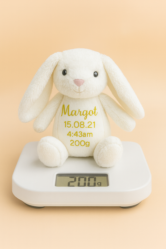 White plush bunny with exact birth weight embroidered on belly atop scale