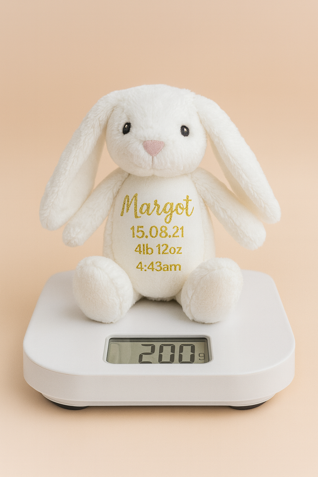 White plush bunny with embroidered exact birth weight on belly atop scale